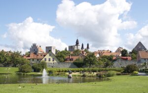 Visby skyline med historiska byggnader och en park i förgrunden på en solig dag.